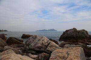 A rocky shoreline with a large island in the distance photo