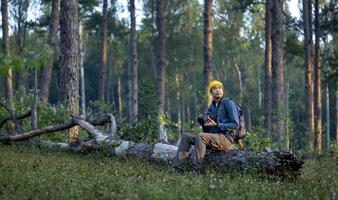 Asian photographer is taking photo of the new discovering bird species while exploring in the pine forest for surveying and locating rare biological diversity and ecologist on field study