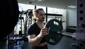 Caucasian muscular body builder sport man is practice weight training on barbell for core muscle inside the gym with dark background for exercising and workout photo