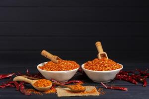 Chili powder, dried chilies, spicy condiments in a bowl placed on a table, dark background. photo