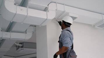 African worker install ducted pipe system for ventilation and air conditioning in office video