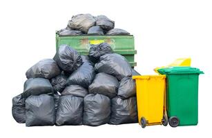 A giant stack of garbage dump with black plastic bags and wheeled plastic bin or can isolated on white background with clipping path Concept of environment photo