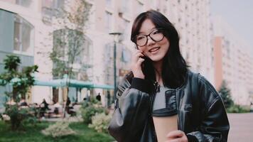 Young woman talking on phone and holding coffee in urban setting video