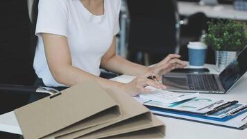 Asian Businesswoman Using laptop computer and working at office with calculator document on desk, doing planning analyzing the financial report, business plan investment, finance analysis concept. video