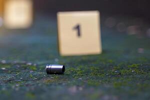Bullet casings fall on cement floor and blurred background of evidence number sign at shooting scene. Concept of investigation, forensics, evidence, forensic science. photo