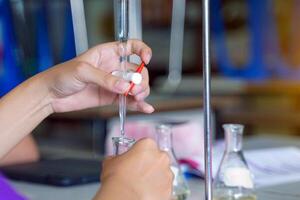 Close-up of a student performing an acid-base titration experiment. Concept of chemistry lab, science, experiment, skills, learning. photo