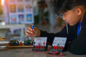 Thai boy performs an outdoor science experiment on connecting a simple electrical circuit by connecting light bulbs in series and observing their brightness. photo