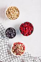 Frozen red, white, black currants and viburnum in cups on the table top and vertical view photo