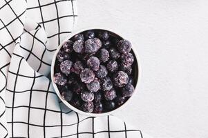 Close up of frozen blackcurrants in bowl on table top view photo