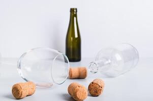 Refusal of alcohol, wine glass and empty bottles lie among corks on the table photo
