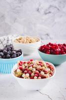 Assorted frozen red, white and black berries in bowls on table vertical view photo
