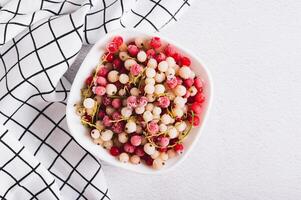 Close up of frozen red and white currants in bowl on table top view photo