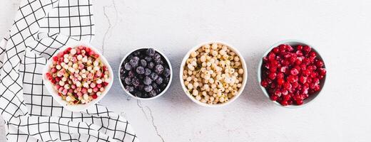 Frozen red, white, black currants and viburnum in cups on the table top view web banner photo