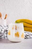 Alternative lactose free banana milk in a glass on the table vertical view photo