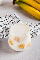 Banana vegan alternative milk in glass and fruits on table vertical view photo