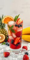 Refreshing fruit cocktail with berries and citrus in a tall glass on a bright table photo