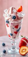 Creamy dessert served in a glass filled with fresh strawberries and blueberries topped with ice cubes photo