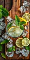 Refreshing glass of mint lemonade with ice and lemon slices on wooden table surrounded by fresh mint leaves photo