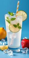 Refreshing citrus drink served in a clear glass with mint, ice, and fresh fruits on a blue background photo