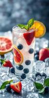 Refreshing summer beverage with fruits and ice in a clear glass on a bright surface photo