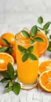 Refreshing orange drink garnished with mint and surrounded by fresh oranges on a light surface photo