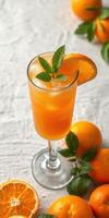 Refreshing orange cocktail garnished with mint on a light background surrounded by fresh oranges photo