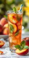 Refreshing peach iced tea garnished with mint leaves served in a tall glass photo