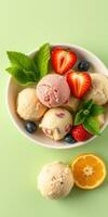 Colorful assortment of fruit-flavored ice cream in a bowl with fresh strawberries and mint leaves on a light green background photo