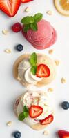 Colorful scoops of ice cream with fresh fruits and mint leaves arranged on a white surface photo