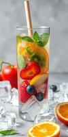 Refreshing fruit cocktail with ice and mint in a tall glass on a marble surface photo