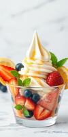 Delicious swirl of soft serve ice cream topped with fresh fruits in a clear cup at a summer gathering photo