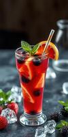 Refreshing fruit cocktail served in a tall glass garnished with berries and mint on a festive table photo