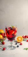 Refreshing fruit punch with berries and citrus served in a glass beside fresh fruits on a marble surface photo