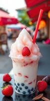 Delicious dessert with fluffy pink topping served in a clear cup beside fresh strawberries at a vibrant outdoor area photo