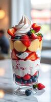 Delicious fruit parfait served in a clear glass with layers of whipped cream, strawberries, and blueberries at a dessert shop photo