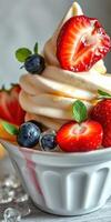 Delicious frozen yogurt topped with fresh strawberries, blueberries, and mint leaves served in a white bowl photo