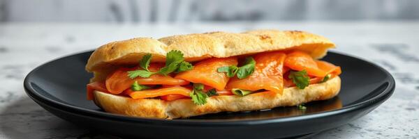 Freshly prepared sandwich filled with smoked salmon and herbs on a black plate photo
