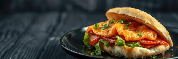 Delicious sandwich with fresh vegetables and melted cheese served on a black plate photo