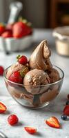 Chocolate ice cream served with fresh strawberries in a clear bowl on a marble countertop during afternoon light photo