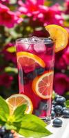 Refreshing summer drink with citrus and berries in a vibrant garden setting photo