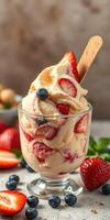 Delicious strawberry and blueberry ice cream served in a glass with a wooden spoon on a light surface photo