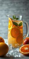 Refreshing citrus drink in a glass pitcher with ice and fresh fruit on a light background photo