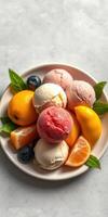 Colorful scoop of ice cream with fresh citrus fruits and mint leaves garnishing a white plate on a light surface photo