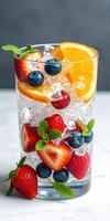 Refreshing berry and citrus cocktail in a glass with ice on a marble counter photo