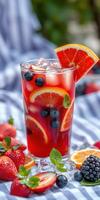 Refreshing summer drink with mixed berries and citrus on a vibrant striped tablecloth photo