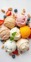 Assortment of colorful ice cream scoops with fresh fruits and nuts displayed on a white plate photo