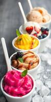 Colorful assortment of frozen desserts in small cups with fresh fruits on a wooden table photo