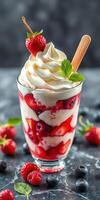 Delicious berry parfait topped with whipped cream and fresh fruit in a glass cup photo