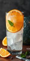 Refreshing orange beverage with ice and mint garnished on a wooden table during a sunny day photo