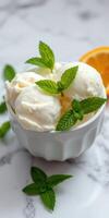 Delicious creamy ice cream served in a white bowl garnished with fresh mint leaves and orange slices photo